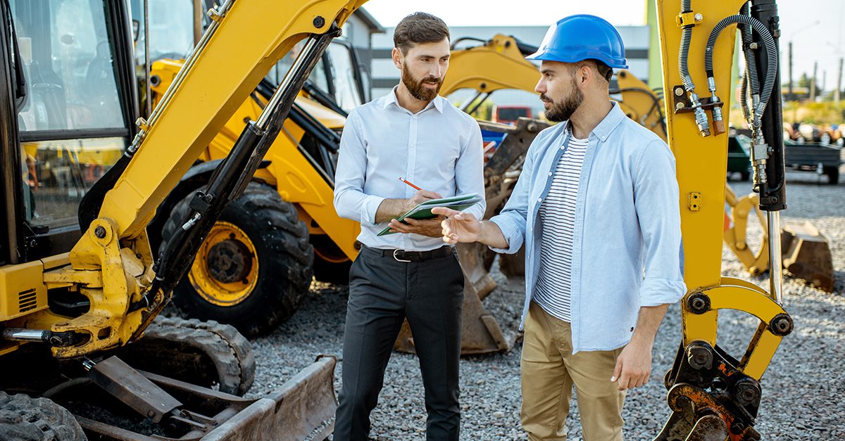 Two men standing in front of construction equipment