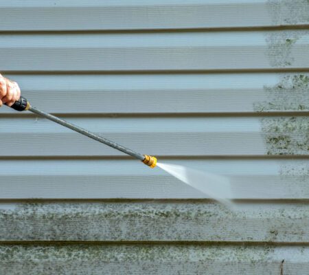 Man power washing mold off of siding